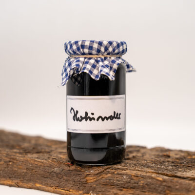 Schwarze Flasche mit kariertem Stoffverschluss auf einem Holztisch