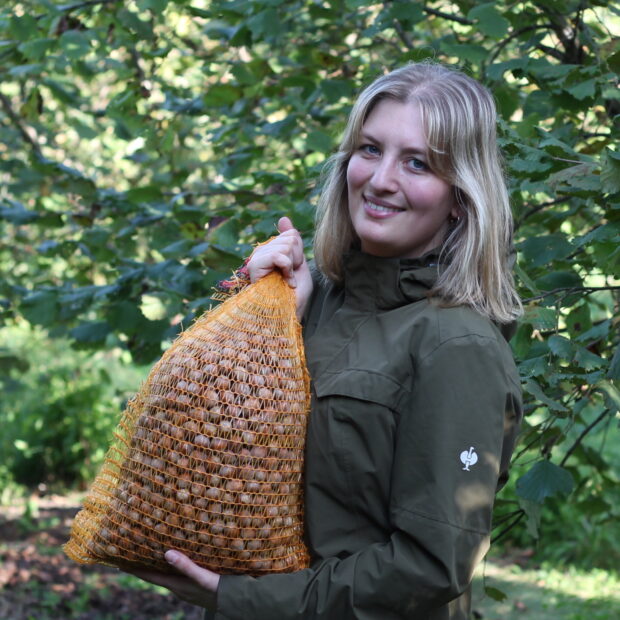 Frau hält Beutel mit Nüssen im Obstgarten